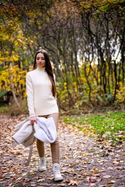 Güzel bayan parkta yürüyor. Açık havada poz veren zarif bir genç kadın..