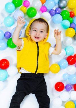 Childhood playground lying. Little kid playing in pool with balls. clipart