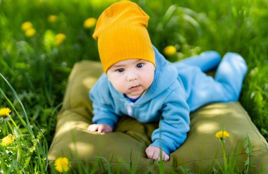 Güzel çimenli bir ortamda yumuşak bir yastığın üzerinde dinlenen huzurlu bir bebek. Çimlerin üzerinde yastığa uzanmış bir bebek