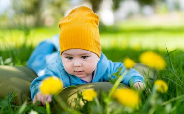 Sarı şapkalı bir bebek çimenlerde yatıyor. Çimenlerde yatan sarı şapkalı şirin bir bebek.