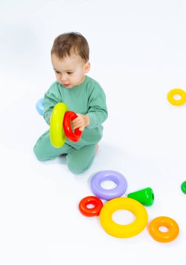 Mutlu bebek yerde bir oyuncakla oynuyor / Yerde oturan bir bebek bir oyuncakla oynuyor