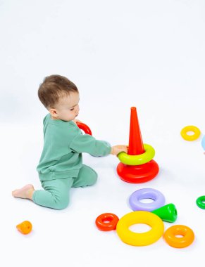 Yerde renkli bir oyuncakla oynayan neşeli bir bebek. Yerde oyuncakla oynayan bir bebek.