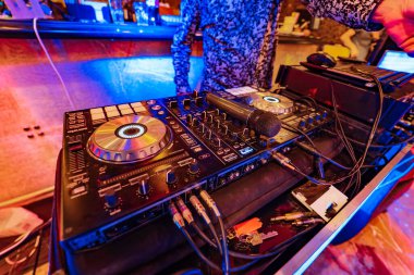 İyi aydınlatılmış bir odada geniş bir ekipman yelpazesine sahip profesyonel bir DJ. Bir sürü ekipmanla dolu bir odada bir DJ.
