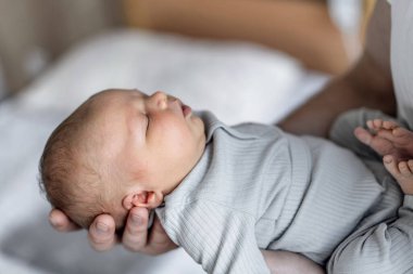 Bir kaç aylık çocuğun kolunu tutmak. Ellerinde küçük bir bebek.