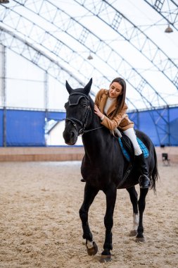 At biniciliği eğitimi alan güzel bir bayan. Ata binen genç bir kadın.