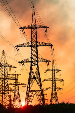 Elektrik kablolarının arkasında günbatımı parıltısı. Güneş, elektrik hatlarının arkasında batıyor.