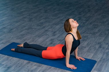Bir kadın mavi bir mindere yoga pozu veriyor.