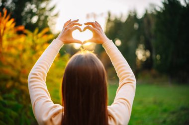 Ellerini kalp şeklinde tutan bir kadın var. Yürek ısıtan bir jest Bir Kadının Elleri Tarafından