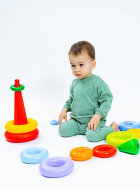 Renkli Oyuncaklar Koleksiyonuyla çevrili Oyuncak Bebek. Oyuncak setinin önünde oturan bir bebek.