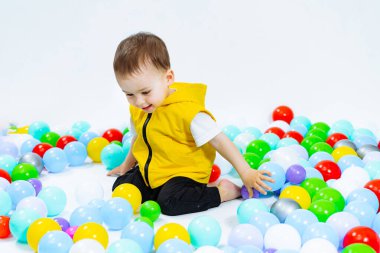 Balonlarla çevrili yerde oturan küçük bir çocuk. Renkli Balonlarla çevrili Neşeli Çocuk