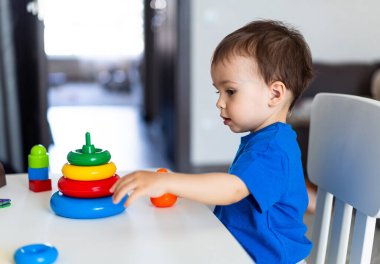 Oyuncu bir çocuk istifleme eğlencesine daldı. Küçük bir çocuk bir oyuncakla oynuyor.