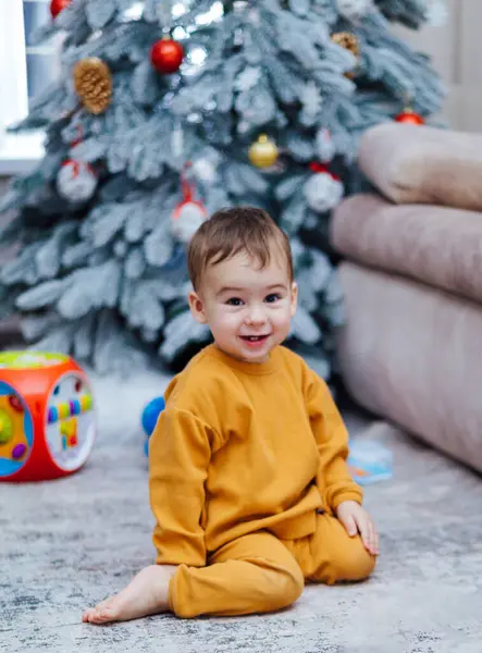 Ένα Μικρό Αγόρι Κάθεται Στο Πάτωμα Δίπλα Ένα Χριστουγεννιάτικο Δέντρο — Φωτογραφία Αρχείου