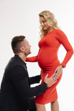 Hamile bir kadının yanında diz çökmüş bir adam. Müstakbel ebeveynler arasında hassas bir an