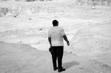 Karla kaplı bir yamacın üzerinde duran bir adam. Karlı yamaçta duran adam