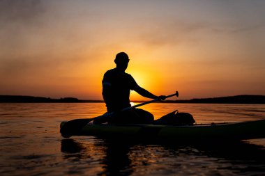 Huzurlu bir an: Kayakta oturan adam, sakin suların tadını çıkarıyor. Sudaki bir kanonun üstünde oturan bir adam.