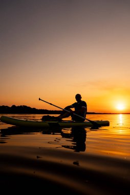 Suyun Üzerinde Sakin Bir Gece: Sunset 'te Kayak Üzerinde Oturan Adam. Gün batımında kanoda oturan bir adam.