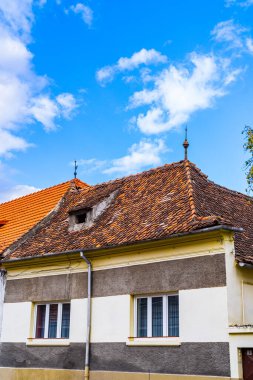 Kırmızı çatılı ve arkasında mavi gökyüzü olan bir bina. Açık mavi gökyüzüne karşı canlı kırmızı çatısı olan renkli bir bina.