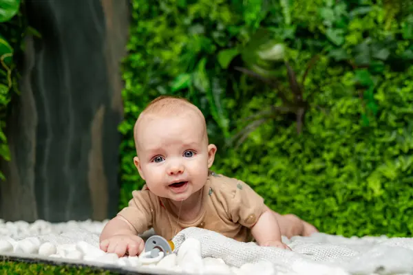 A Serene Baby on a Soft Blanket, Surrounded by a Vibrant Green Wall. A baby laying on a blanket in front of a green wall