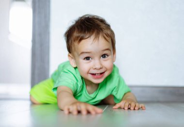 Neşeli Küçük Çocuk. Yüzünde bir gülümsemeyle yerde yatan küçük bir çocuk.