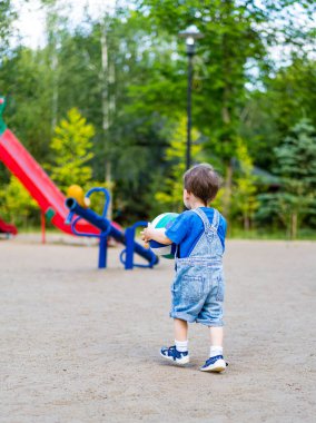 Oyun parkının önünde duran küçük bir çocuk. Neşeli Küçük Çocuğun Neşeli Maceraları Canlı Oyun Alanında