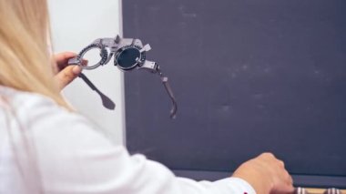 Göz bilimi, görme, tanılama. Optometrist oftalmoloji kliniğinde messbrille tutuyor.