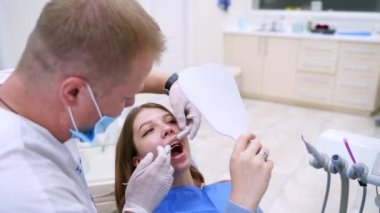 Dişçi koltuğundaki hasta. Genç bayan hasta dişçi muayenehanesini ziyaret ediyor