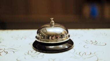 Servis zili klasiği. Otel resepsiyonundaki altın servis çanının el görüntüsünü kapat.