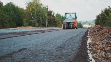 Yol yapımı ekipman makineleri. Asfalt paten kırsalda yeni bir yol açıyor