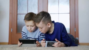 Aletleri olan iki çocuk. Kardeşler evde akıllı telefondan oyun oynuyorlar, modern iletişim ve cihaz bağımlılığı kavramı