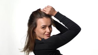 Saç stili kahkahadan titreyen bir kadın. Olumlu gülümsüyor ve beyaz arka planda dururken harika bir ruh hali içinde.