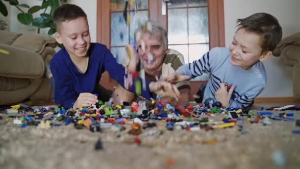 子供たちはレゴで遊ぶ 家で親と一緒にレゴを遊んでいる面白い子供たち — ストック動画