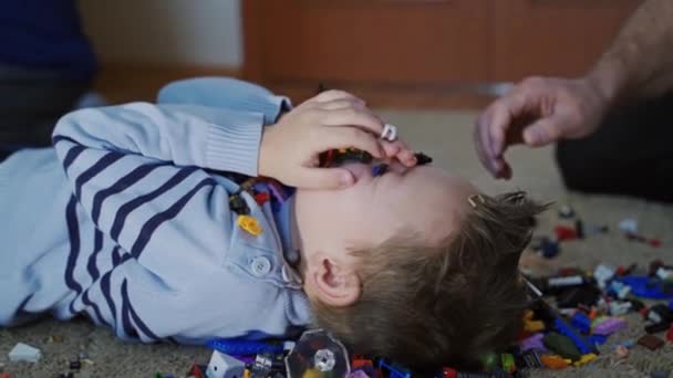 Семья Играет Конструктором Закрыть Вид Падающего Лего Маленького Мальчика Помещении — стоковое видео