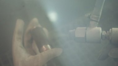 Fabrikada usta bir ressam. Fabrikada çalışan bir işçi barut kaplı bir silahla metal parçaları boyuyor.