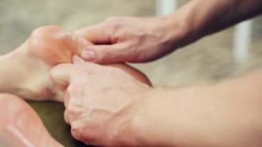 Spa salonunda ayak masajı. Profesyonel terapist spa 'daki bir kadına rahatlatıcı bir refleksoloji uyguluyor.