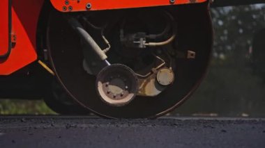 Buharlı silindirle yol püskürtülmüş. Yeni yolda taze sıcak asfalt yuvarlanıyor.