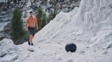 İlaç topuyla fitness antrenmanı. Delikanlı dışarıda sağlık topu kaldırıyor.