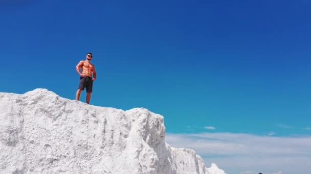スポーツマン山の崖の上に立っている 裸の胴をした男が山の上に立ち自然を楽しむ — ストック動画