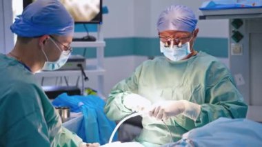 Ekip ameliyathanede çalışıyor. Tıbbi ekip, parlak modern ameliyathanede cerrahi operasyon gerçekleştiriyor.