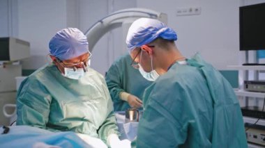 Tıbbi ekip operasyon yapıyor. Ameliyathanede ameliyat ekipmanlarıyla bir grup cerrah.