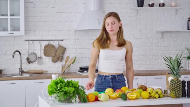 家で主婦の笑顔 軽いキッチンで健康食品を食べるスポーティ若い女性 — ストック動画