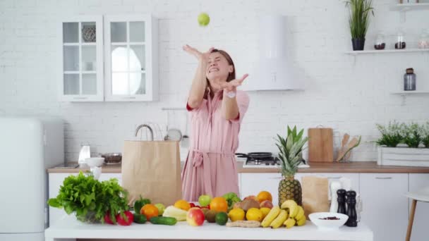 現代の台所で若い女性 笑顔の幸せな女の子の肖像キッチンでリンゴを投げる — ストック動画