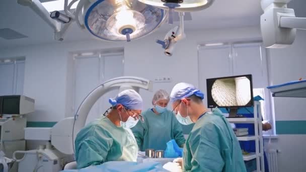 室内で手術チームが活動しています 患者のモニタリングに取り組む外科医チーム — ストック動画