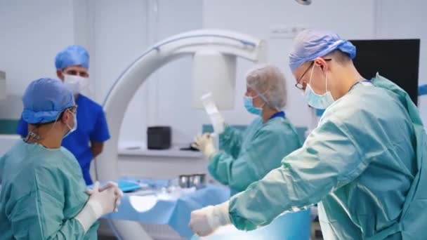 オペレーティング シアターで外科医のグループ 明るい現代オペレーティングルームで外科手術を行う医療チーム — ストック動画