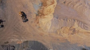 Kazı makinesi kumlu yüzeyde çalışıyor. İnşaat alanında çalışan ağır toprak taşıyıcısının havadan görünüşü