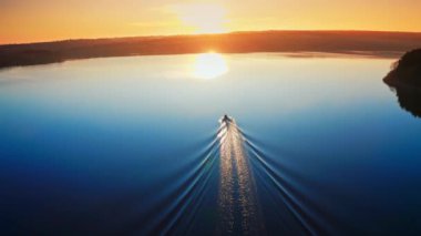 Gün batımındaki hava manzarası. Kamera gün batımına doğru nehir boyunca giden tekneyi takip ediyor.