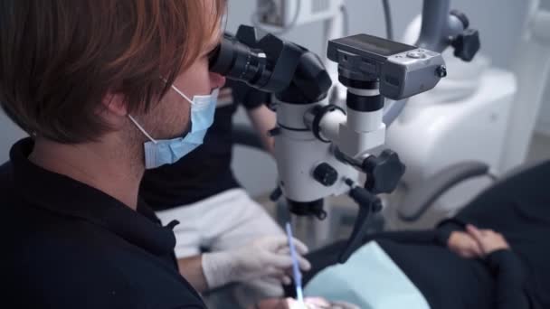 Dentysta Pracy Pacjentem Dentysta Operujący Pacjentkę Przez Mikroskop — Wideo stockowe