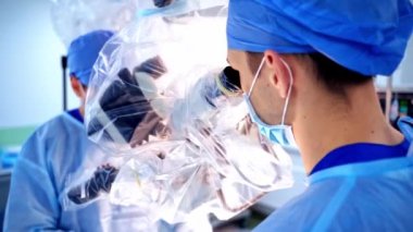 Bir grup doktor bir hastaya ameliyat yapıyor. Ameliyathanede çalışan tıp üniformalı ve maskeli cerrahlar. Nöroşirürji.
