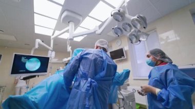 Bir grup doktor bir hastaya ameliyat yapıyor. Ameliyathanede çalışan tıp üniformalı ve maskeli cerrahlar..