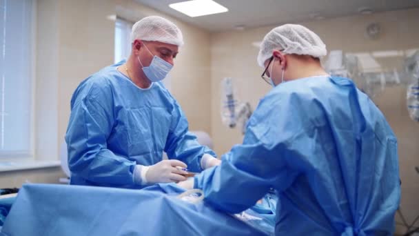 수술실에서 외과의사는 기기를 사용합니다 보호복과 마스크를 의사들은 병원에서 수술을 수행합니다 — 비디오