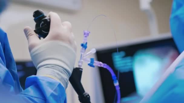 内視鏡手術について 外科医の手は モニターのぼやけた背景に医療機器を保持しています クローズアップ — ストック動画